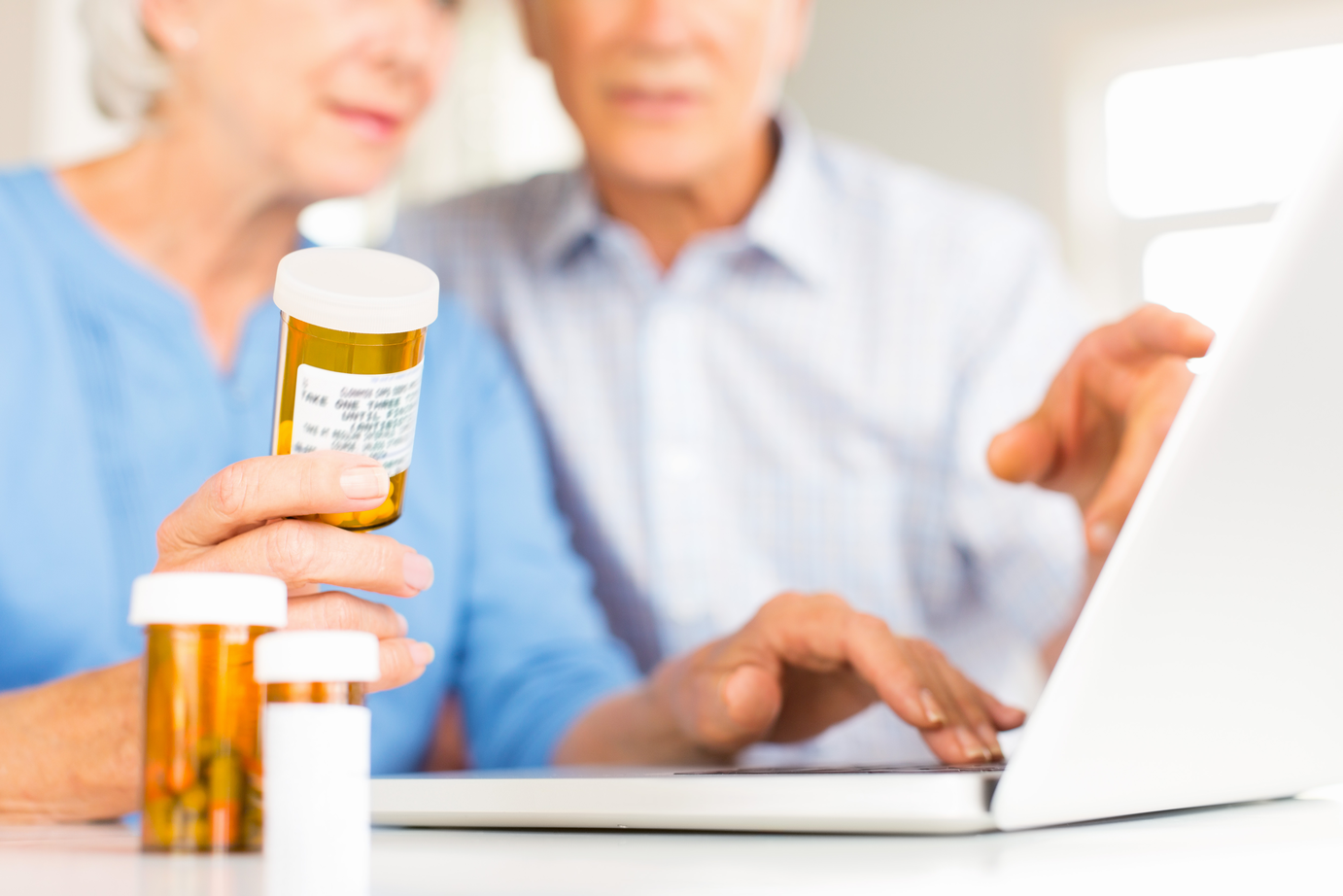 Two folks holding a prescription and look at a computer